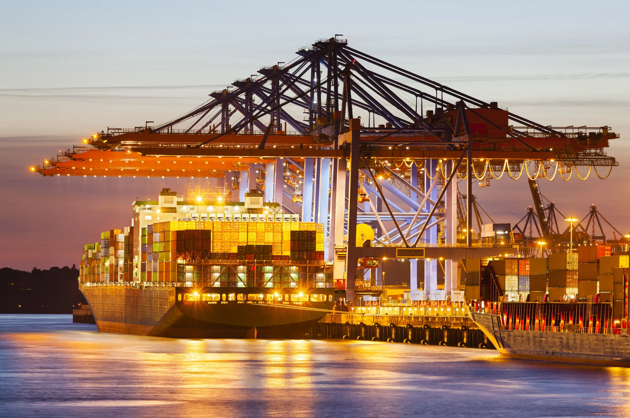 Container terminal at night with stacked shipping containers and gantry cranes